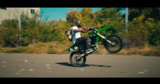 Kaaris au volant d'une moto en roue arrière dans le clip Illimité